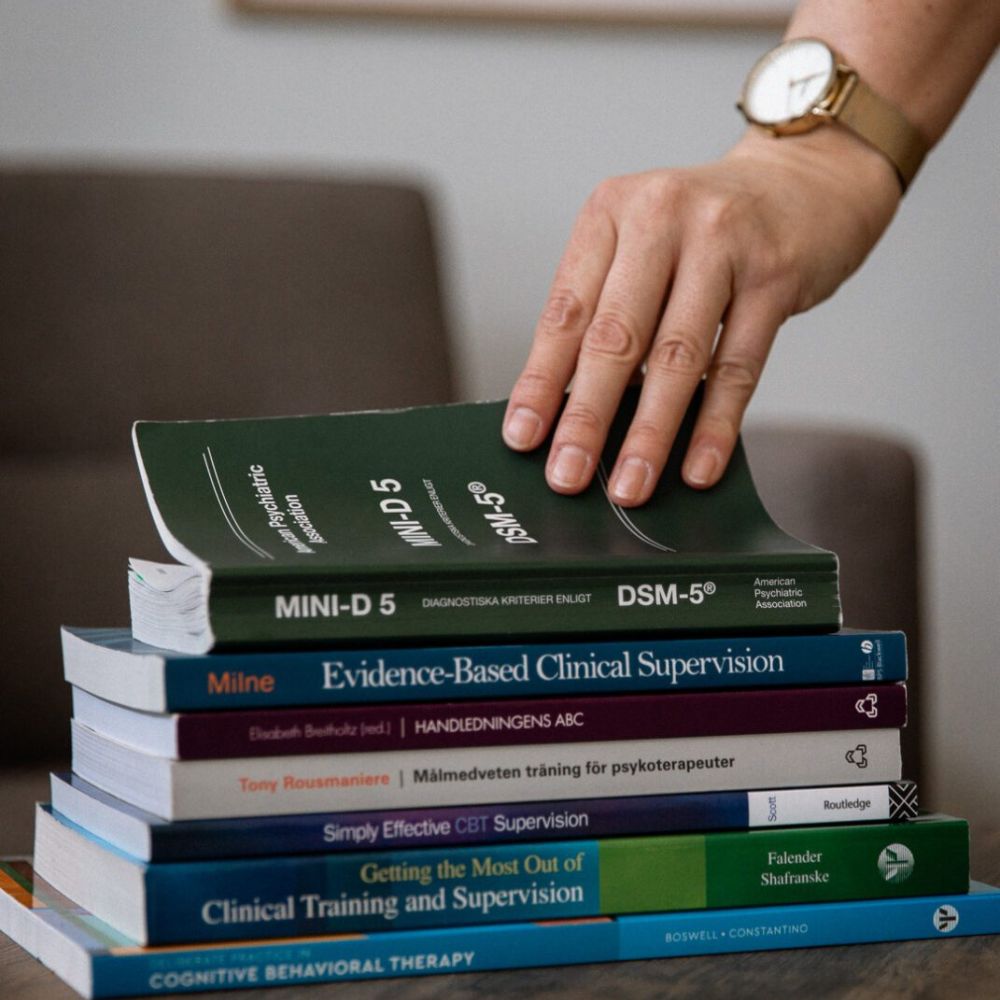 Trave med böcker om handledning av psykolog inom vård och skola.