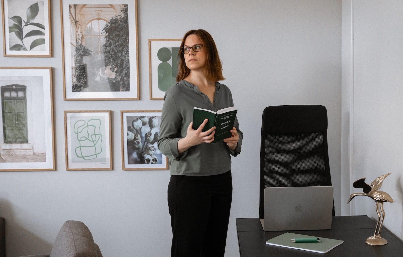 Handledare i psykologiskt utredningsarbete Andrea Sjöström står på kontoret och håller i diagnosmanual